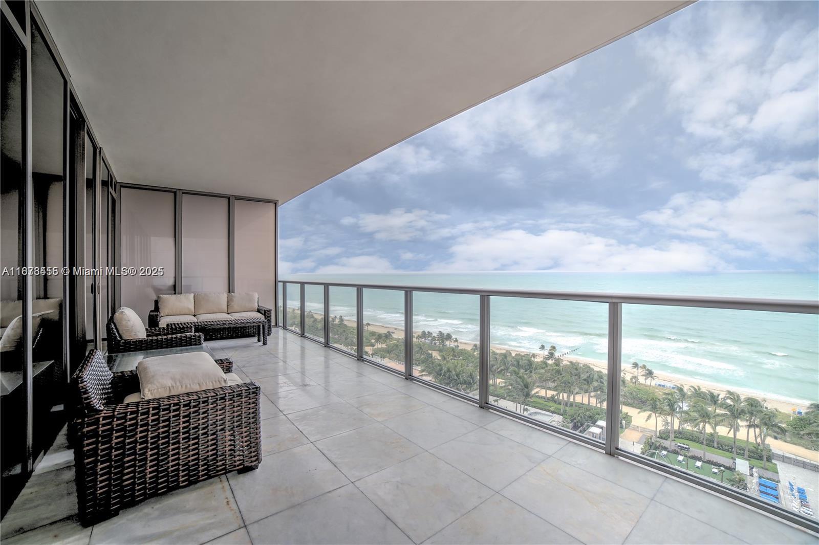 A spacious balcony with wicker furniture overlooks the ocean and a sandy beach — 9705 Collins Ave # 1204N, Bal Harbour FL 33154, BAL HARBOUR, FL
