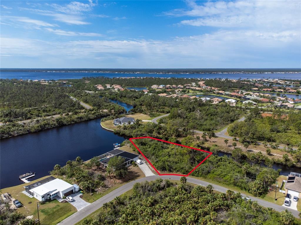 An aerial view shows a vacant, wooded residential lot outlined in red near a canal — 2253 BEURKET STREET, PORT CHARLOTTE, FL