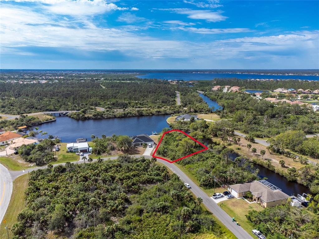 An aerial view shows a vacant, wooded residential lot outlined in red near a canal — 2253 BEURKET STREET, PORT CHARLOTTE, FL