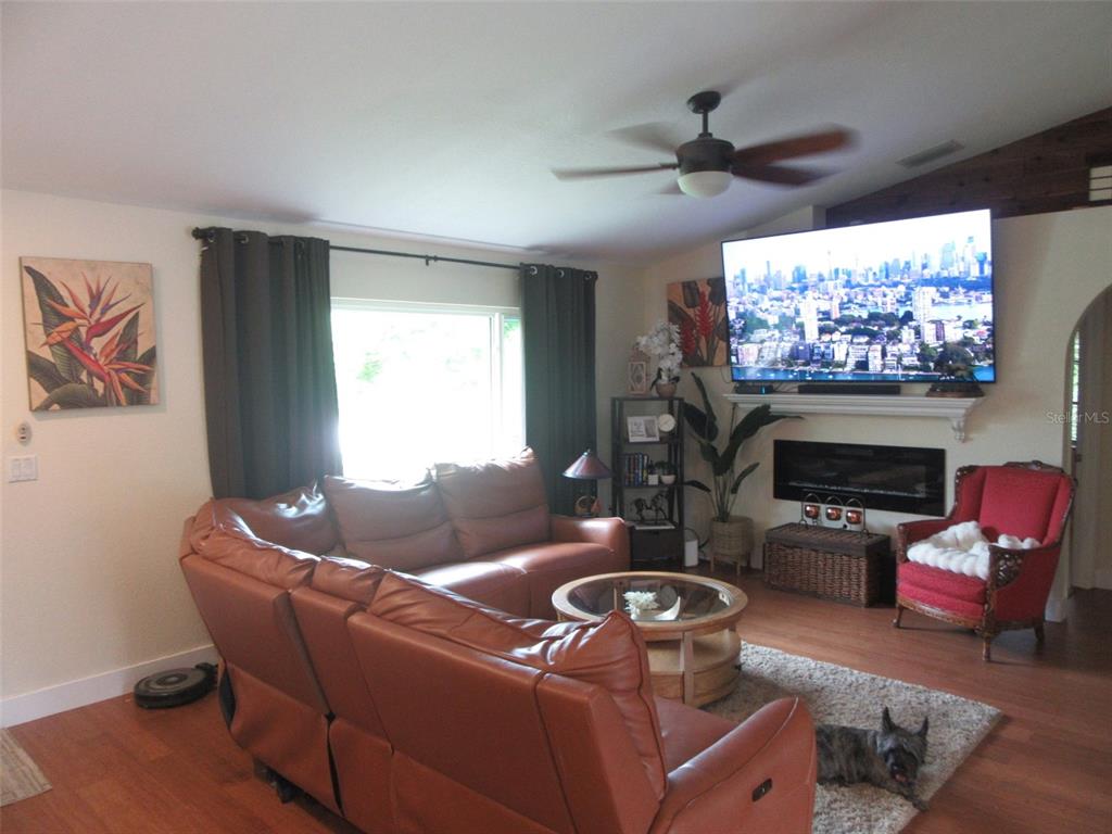 A living room features a leather sectional, a fireplace with a mounted television, and hardwood floors — 4059 MICHEL TREE STREET, PORT CHARLOTTE, FL