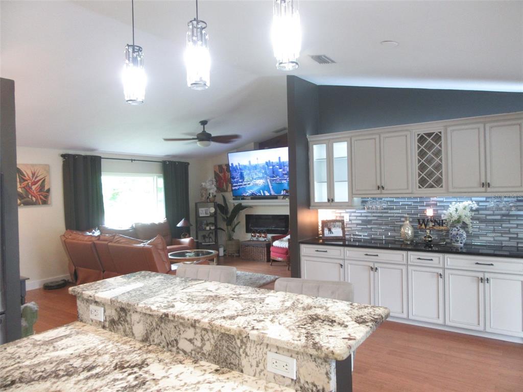 A kitchen with granite countertops and white cabinets overlooks a living room with a fireplace — 4059 MICHEL TREE STREET, PORT CHARLOTTE, FL