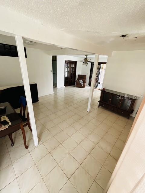 An open-concept living area features light-colored tile flooring, white support columns, and a dark cabinet — C-10 CLL BLANCA, BAYAMON, PR