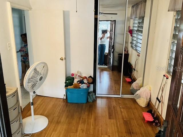 A bedroom features wood-look flooring, a white pedestal fan, a blue toy bin, and mirrored closets — C-10 CLL BLANCA, BAYAMON, PR