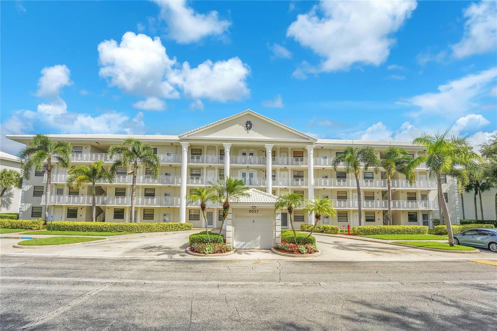 A three-story apartment building features white columns, balconies, and a central covered entrance — 6037 Balboa Circle # 401, Boca Raton FL 33433, BOCA RATON, FL