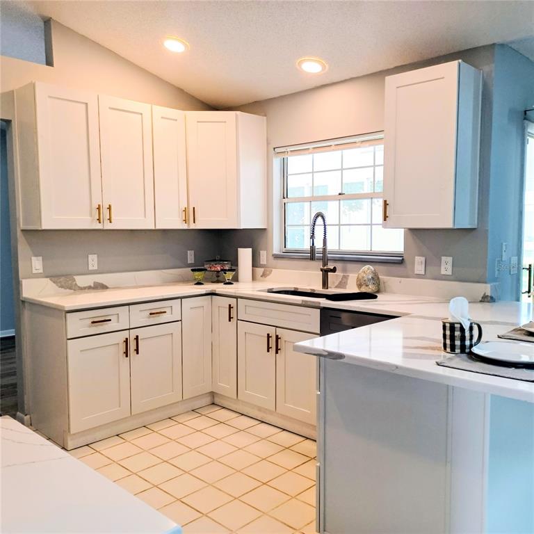 A kitchen with white cabinets, light countertops, and a sink beneath a window — 18 WESTCLIFFE LANE, PALM COAST, FL