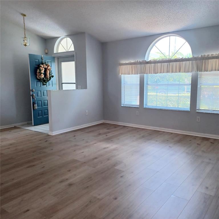 A living room with light gray walls, wood-look flooring, a blue front door, and arched windows — 18 WESTCLIFFE LANE, PALM COAST, FL