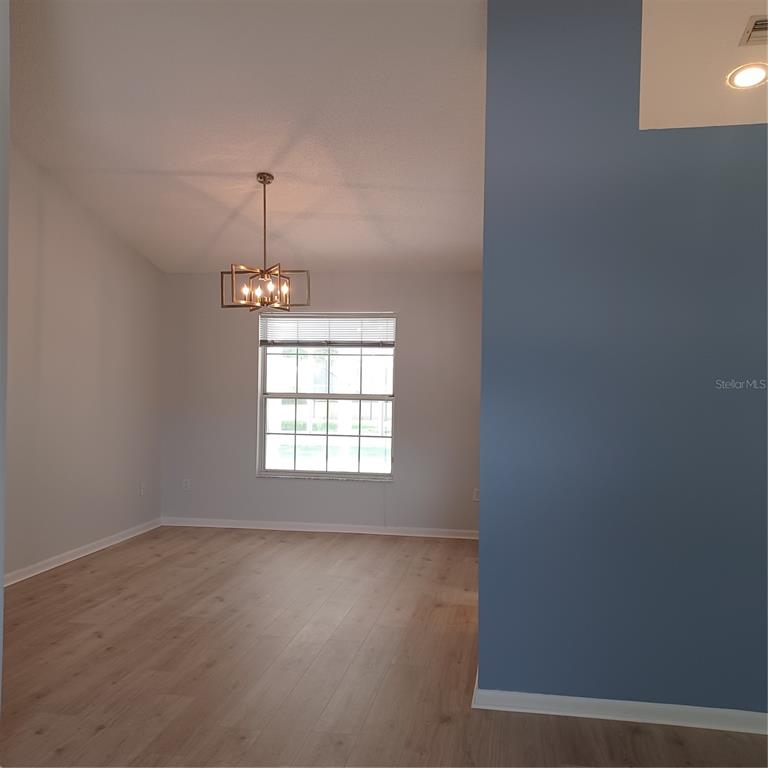 A dining area features light wood flooring, a modern chandelier, and a large window — 18 WESTCLIFFE LANE, PALM COAST, FL