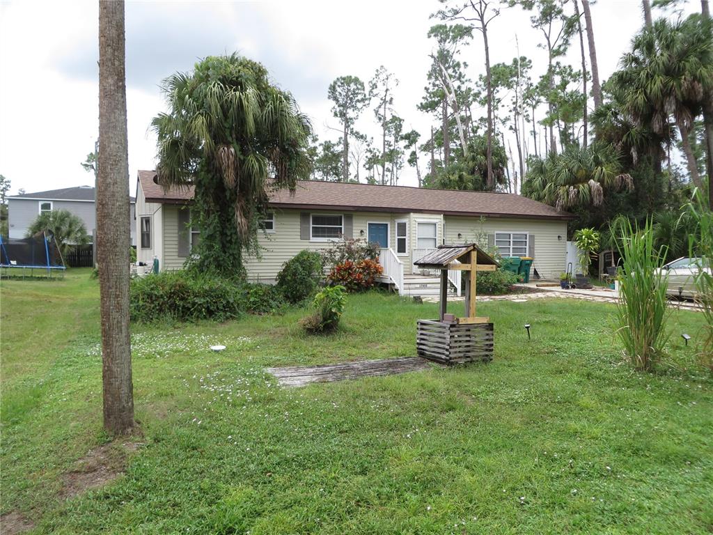 A single-story house with light siding and a wooden wishing well in the front yard — 17455 MASTEN AVENUE, PORT CHARLOTTE, FL