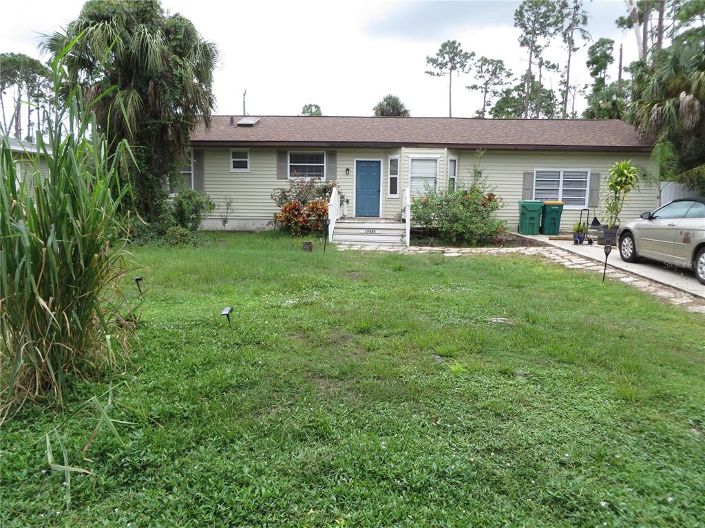 A single-story house with light siding, a blue front door, and a grassy front yard — 17455 MASTEN AVENUE, PORT CHARLOTTE, FL
