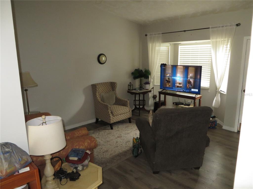 A living room features a patterned armchair, a dark recliner, a television, and wood-look flooring — 17455 MASTEN AVENUE, PORT CHARLOTTE, FL