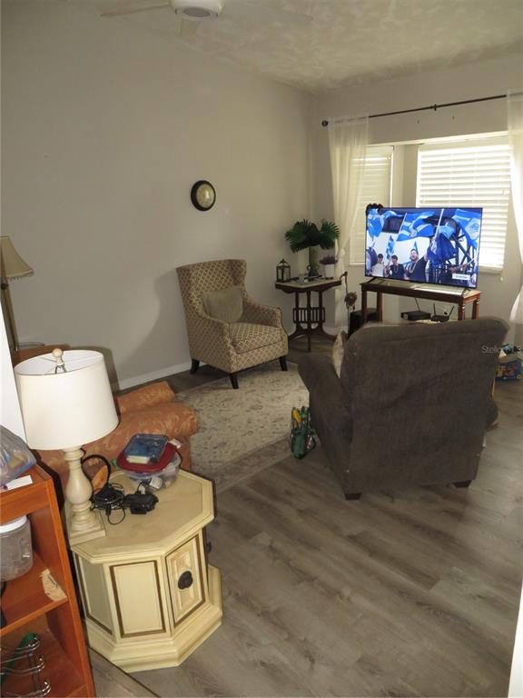 A living room features wood-look flooring, a patterned armchair, a recliner, and a television — 17455 MASTEN AVENUE, PORT CHARLOTTE, FL