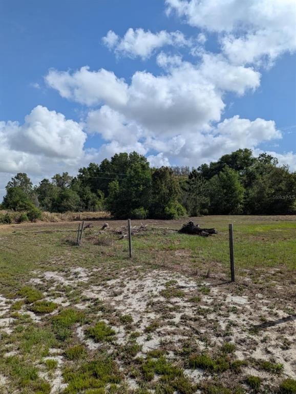 A grassy, sandy lot features a wire fence and scattered debris under a cloudy sky — 3465 W ANSONIA ROAD, AVON PARK, FL