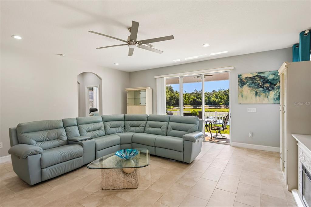 A living room features a light blue sectional sofa, a glass coffee table, and sliding doors — 15914 CEDAR ELM TERRACE, LAND O LAKES, FL