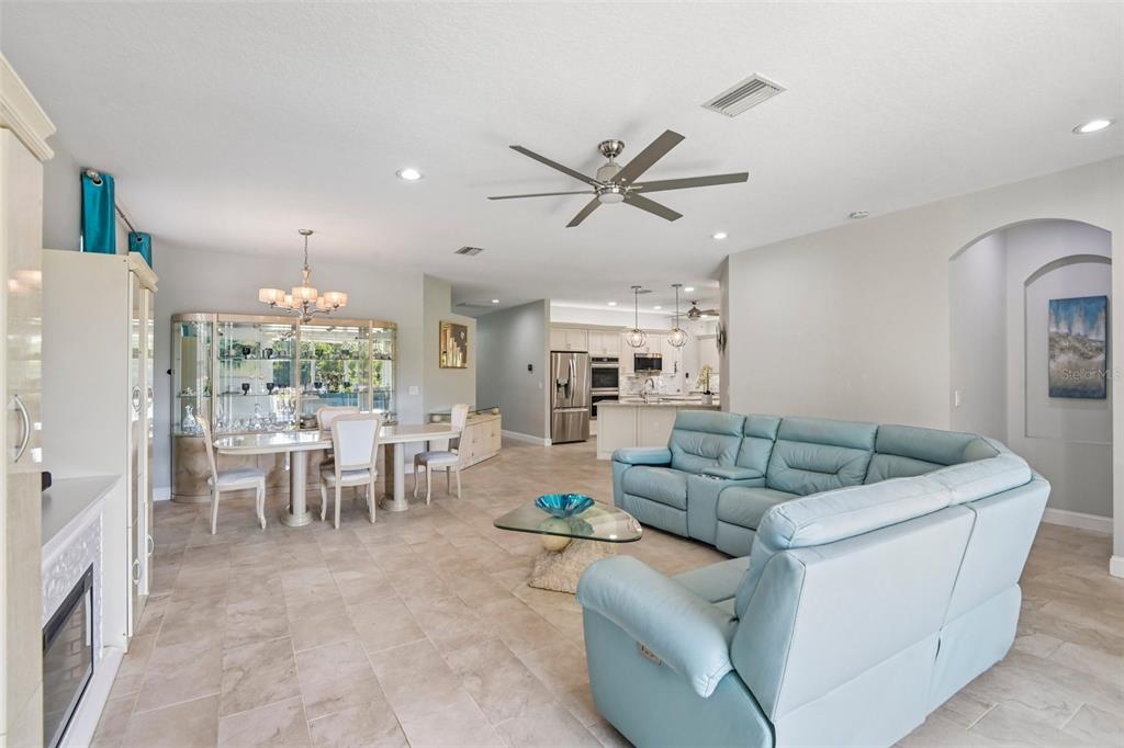 An open-concept living and dining area features light tile flooring and a blue sectional sofa — 15914 CEDAR ELM TERRACE, LAND O LAKES, FL