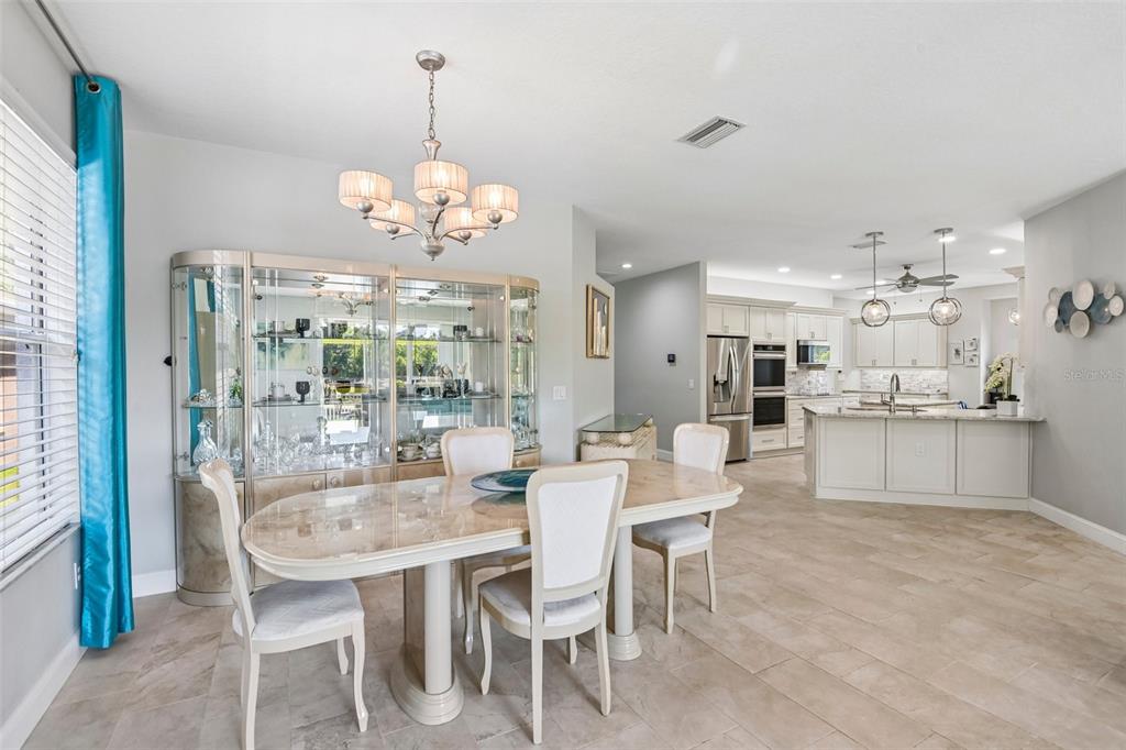 A dining area with a glass china cabinet and table opens into a white kitchen — 15914 CEDAR ELM TERRACE, LAND O LAKES, FL