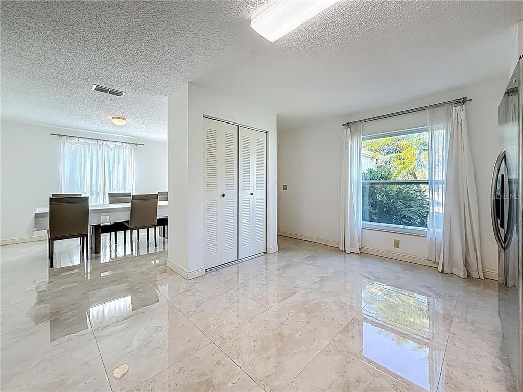 A dining area with tile flooring, white walls, louvered closet doors, and a large window — 1909 CASTLE BAY COURT, OLDSMAR, FL