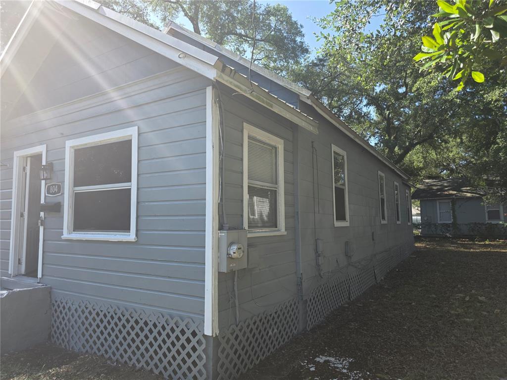 A gray, single-story house with white trim and lattice skirting sits under large trees — 804 W 29TH STREET, JACKSONVILLE, FL