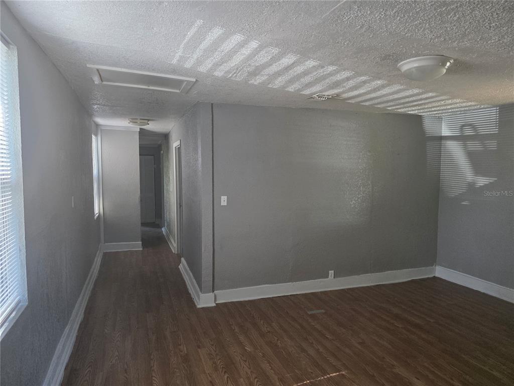 An empty room features gray walls, wood-look flooring, and a hallway leading to other rooms — 804 W 29TH STREET, JACKSONVILLE, FL