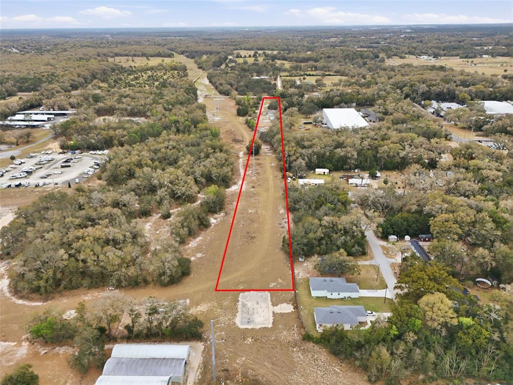 An aerial view shows a long, narrow, cleared plot of land outlined in red — 24629 SORRENTO AVENUE, SORRENTO, FL