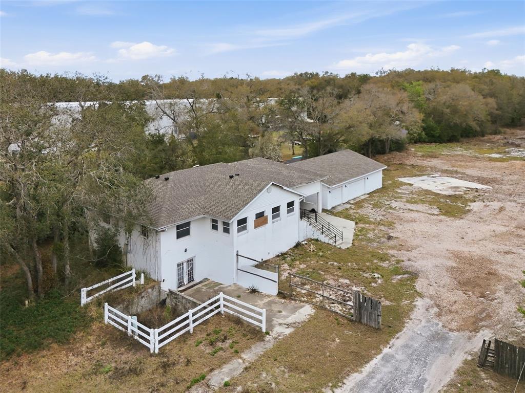 An elevated exterior view shows a white house with a garage and fenced yard — 24629 SORRENTO AVENUE, SORRENTO, FL