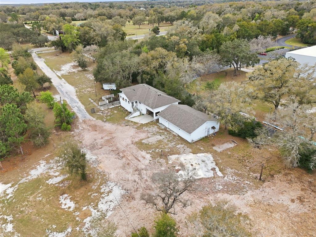 An aerial view shows a white house with a garage on a large, wooded lot — 24629 SORRENTO AVENUE, SORRENTO, FL