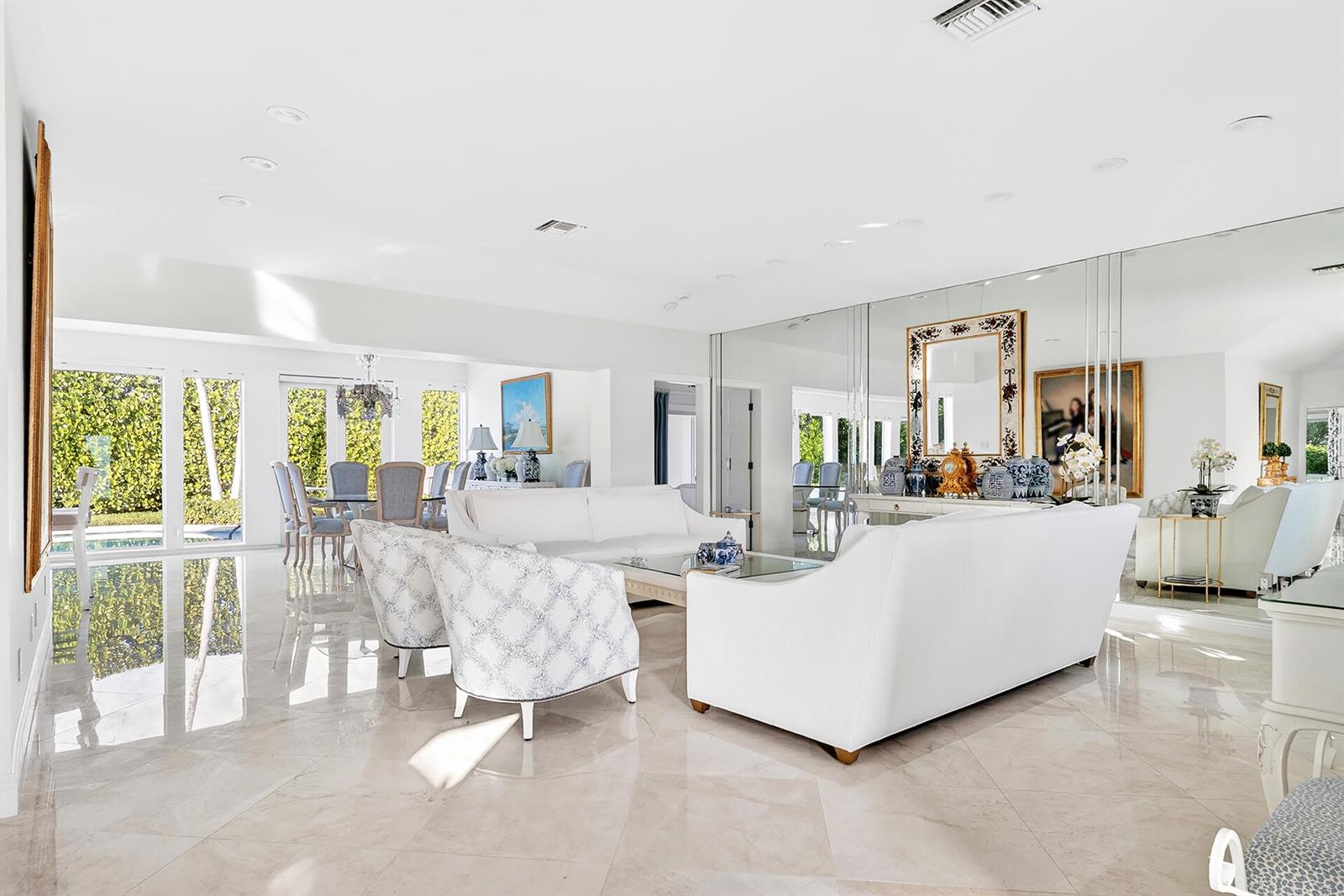 A bright living room features white sofas, patterned armchairs, marble floors, and a mirrored wall — 107 E Inlet Drive, Palm Beach FL 33480, PALM BEACH, FL