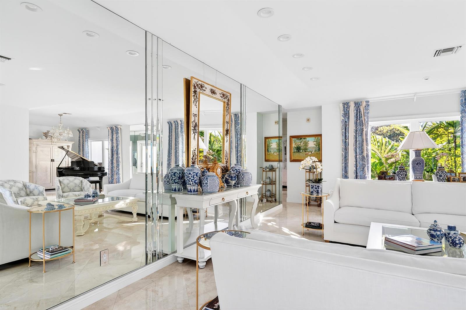 A bright living room features white sofas, blue and white decor, and a mirrored wall — 107 E Inlet Drive, Palm Beach FL 33480, PALM BEACH, FL