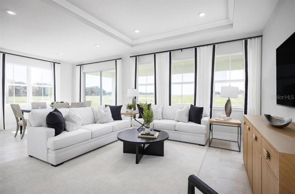 A bright living room features white sofas, a round coffee table, and large windows — 3165 MADRAS DRIVE NW, PALM BAY, FL