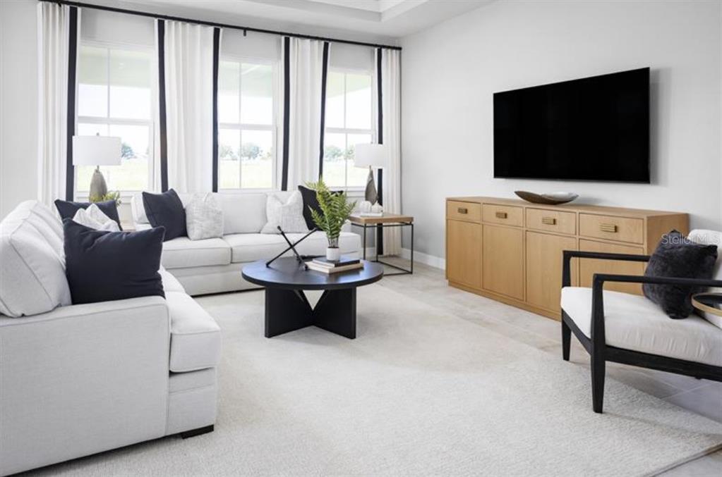 A bright living room features a white sofa, a black coffee table, and a wooden console — 3165 MADRAS DRIVE NW, PALM BAY, FL
