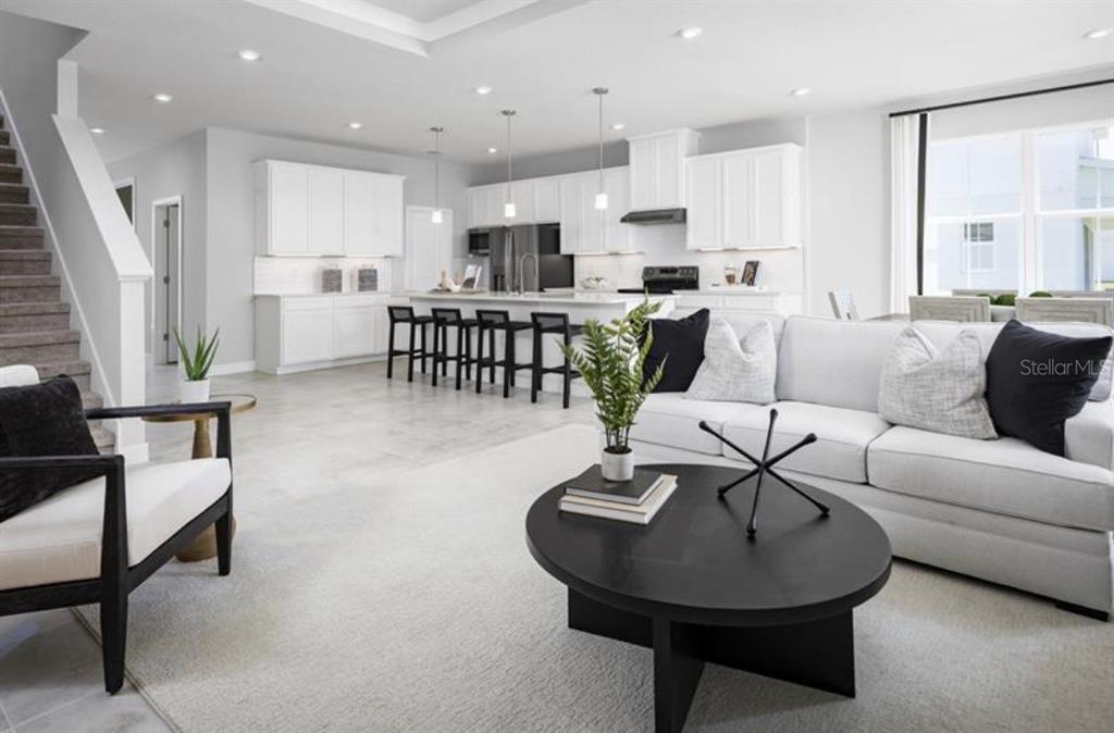 An open-concept living room and kitchen feature white cabinetry, a large island, and neutral furnishings — 3165 MADRAS DRIVE NW, PALM BAY, FL