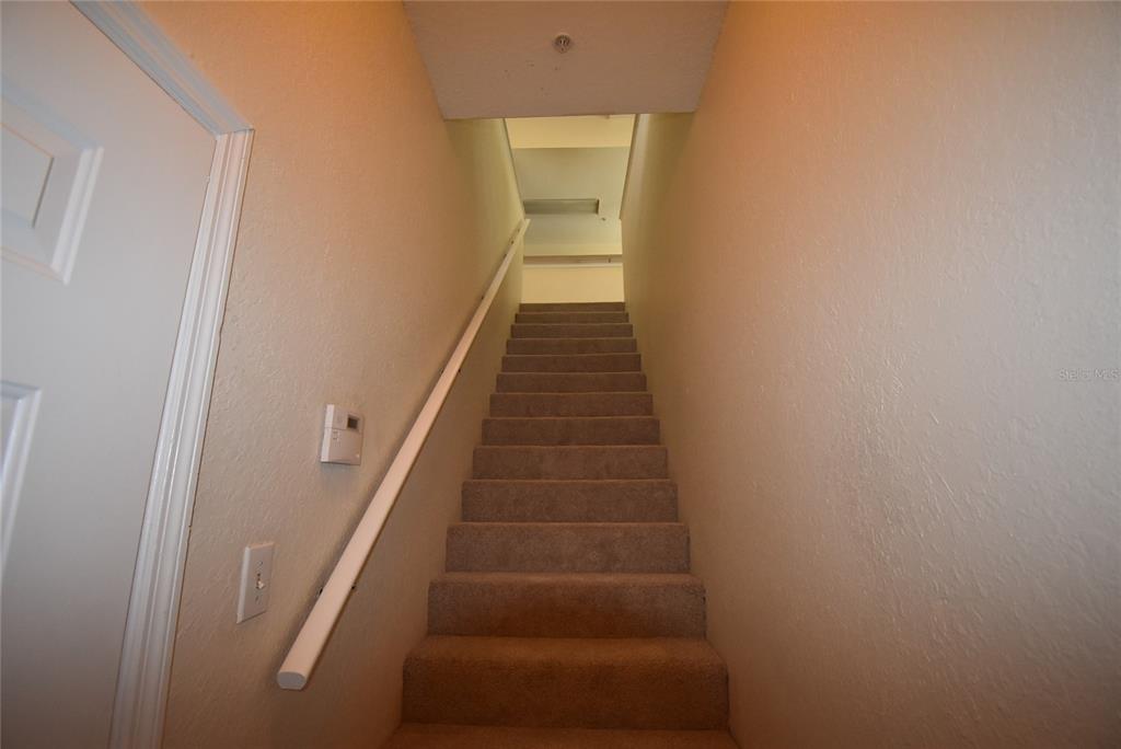 A carpeted staircase with a white handrail leads upward between two plain beige walls — 862 GRAND REGENCY POINT UNIT 205, ALTAMONTE SPRINGS, FL