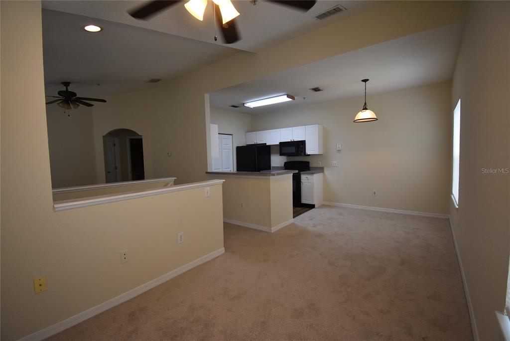 An interior view shows a carpeted living area opening to a kitchen with white cabinets — 862 GRAND REGENCY POINT UNIT 205, ALTAMONTE SPRINGS, FL