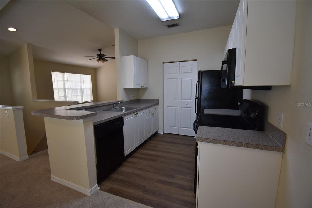 A kitchen features white cabinets, dark countertops, black appliances, and wood-look flooring — 862 GRAND REGENCY POINT UNIT 205, ALTAMONTE SPRINGS, FL