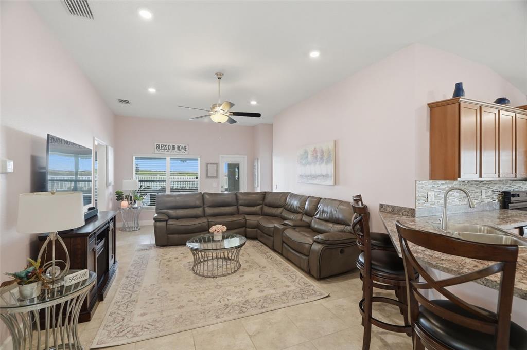 A living room with a brown sectional sofa, a glass coffee table, and a kitchen counter — 14449 POTTERTON CIRCLE, HUDSON, FL