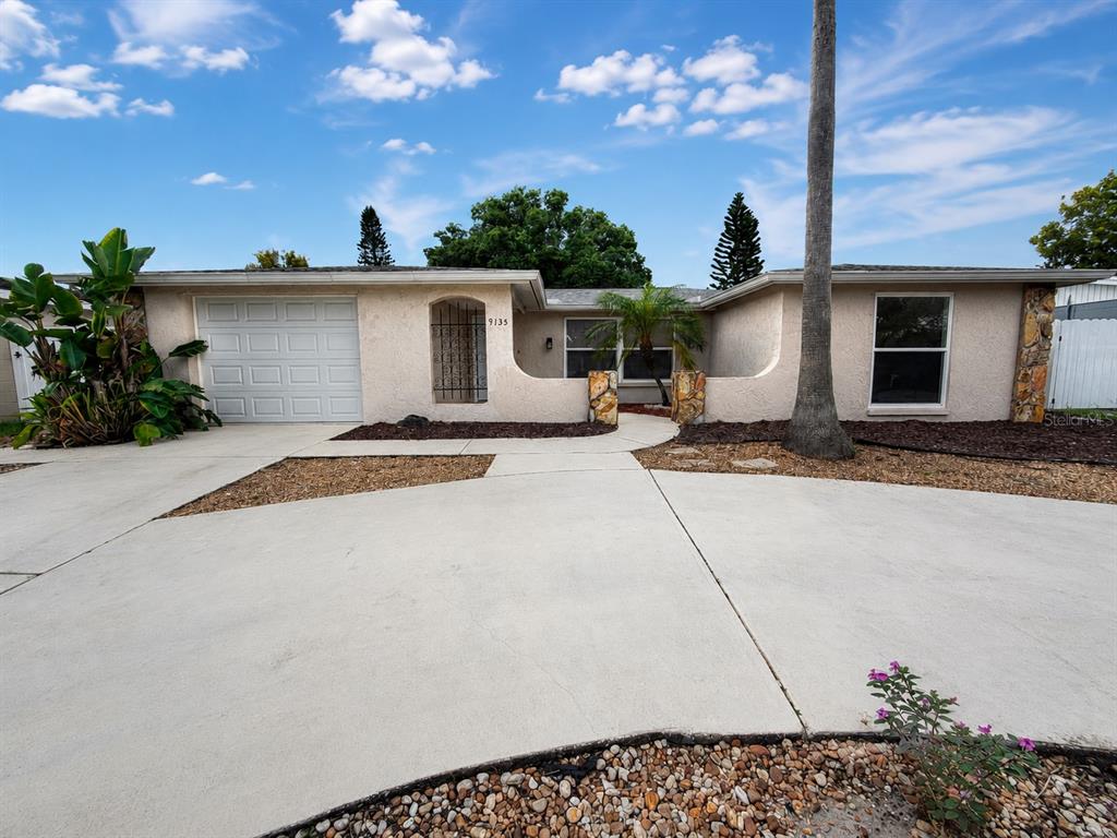 A single-story house with a stucco exterior, a garage, and a curved front entryway — 9135 GREENBRIAR LANE, PORT RICHEY, FL