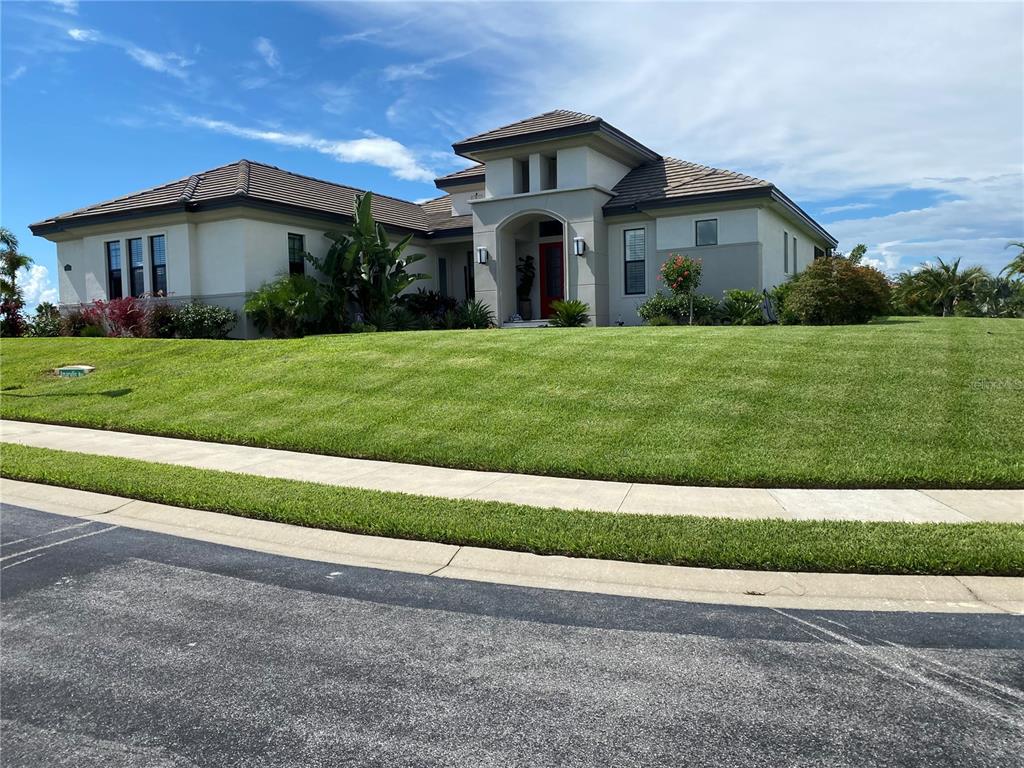 A single-story house with a red front door sits behind a large, sloped grassy lawn — 262 AMARYLLIS WAY, LAKE ALFRED, FL