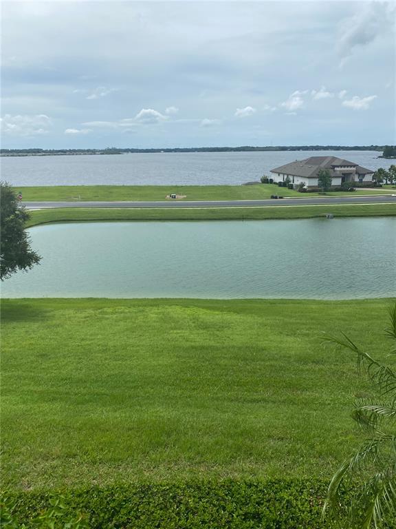 A grassy lawn overlooks a small pond with a large lake and house in the background — 262 AMARYLLIS WAY, LAKE ALFRED, FL
