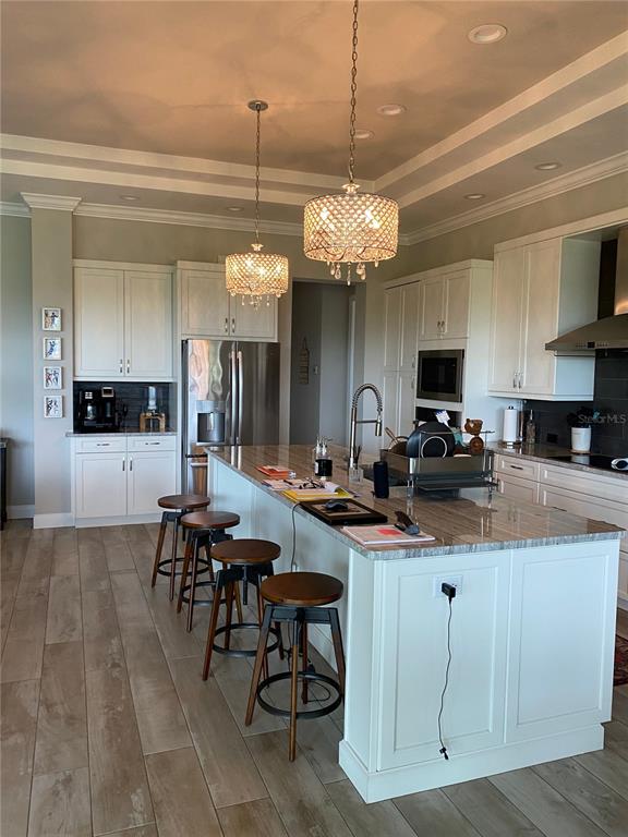 A kitchen features white cabinetry, a large island with bar stools, and two crystal chandeliers — 262 AMARYLLIS WAY, LAKE ALFRED, FL