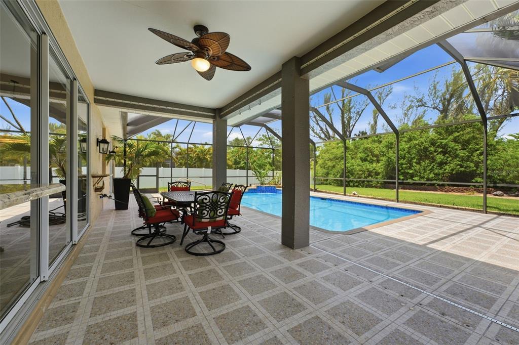 A covered patio with tile flooring overlooks a screened-in swimming pool and backyard — 5936 SW 1ST COURT, CAPE CORAL, FL