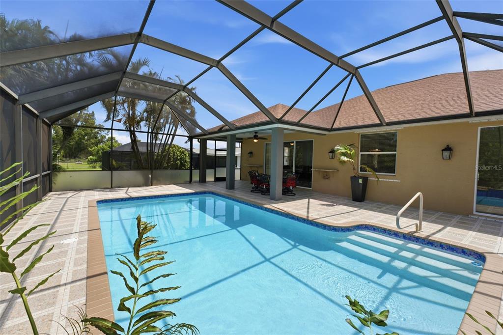 A screened-in swimming pool with steps and a covered patio area with outdoor furniture — 5936 SW 1ST COURT, CAPE CORAL, FL