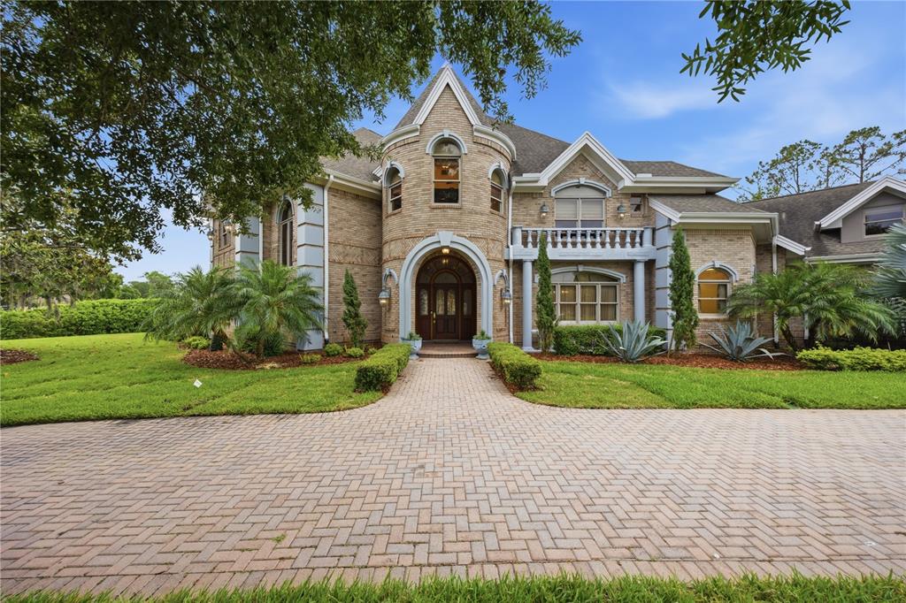 A two-story brick house with a turreted entrance, arched doorway, and a paved driveway — 4123 HIGHLAND PARK CIRCLE, LUTZ, FL