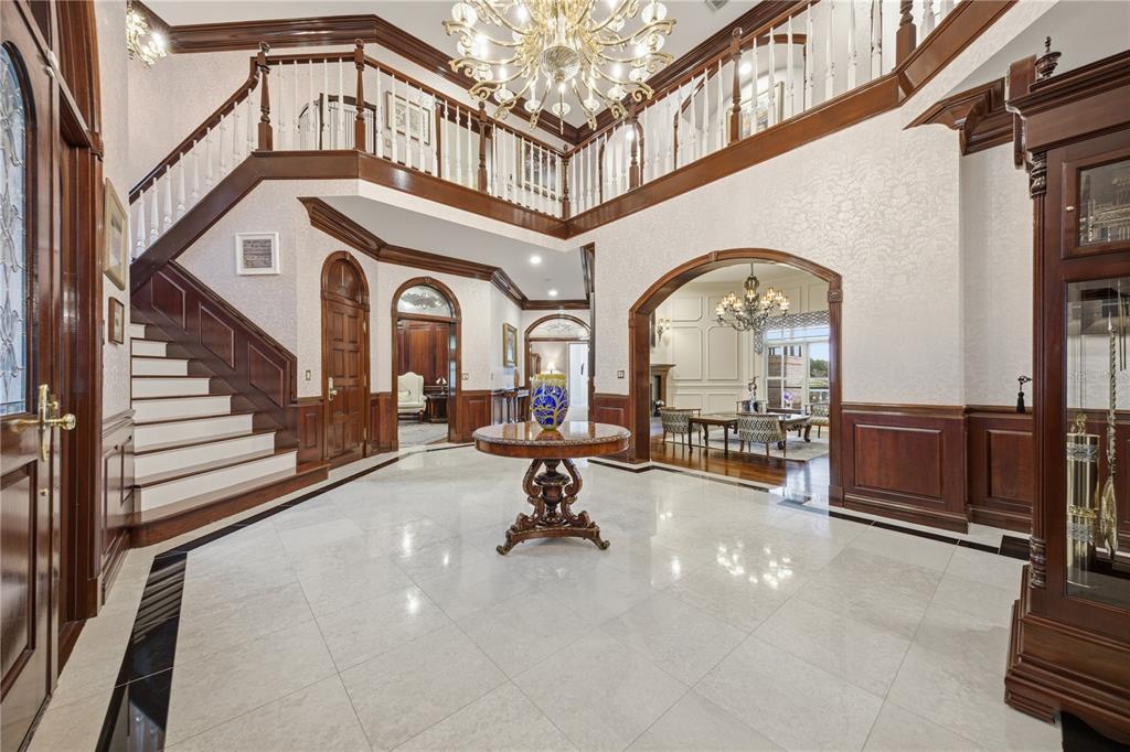 A grand foyer features a marble floor, a central pedestal table, and a wooden staircase — 4123 HIGHLAND PARK CIRCLE, LUTZ, FL