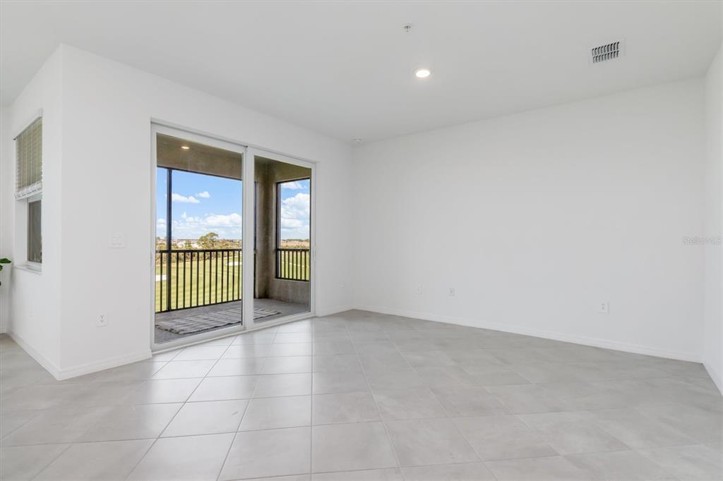 An empty room with white walls, light tile flooring, and a sliding door to a balcony — 17595 OPAL SAND DRIVE UNIT 406, VENICE, FL