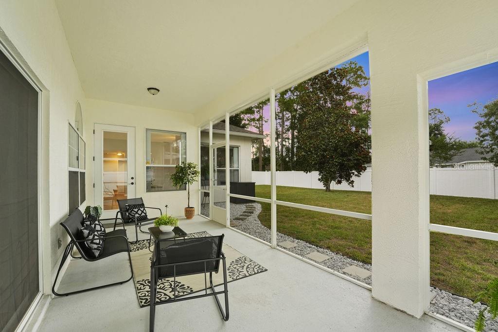 A screened-in patio features outdoor furniture, a concrete floor, and a view of the backyard — 58 RYBERRY DRIVE, PALM COAST, FL