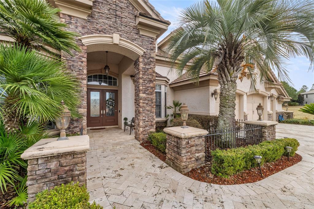The exterior of a house features stone accents, a paved walkway, and palm trees — 6861 SW 179TH AVENUE ROAD, DUNNELLON, FL