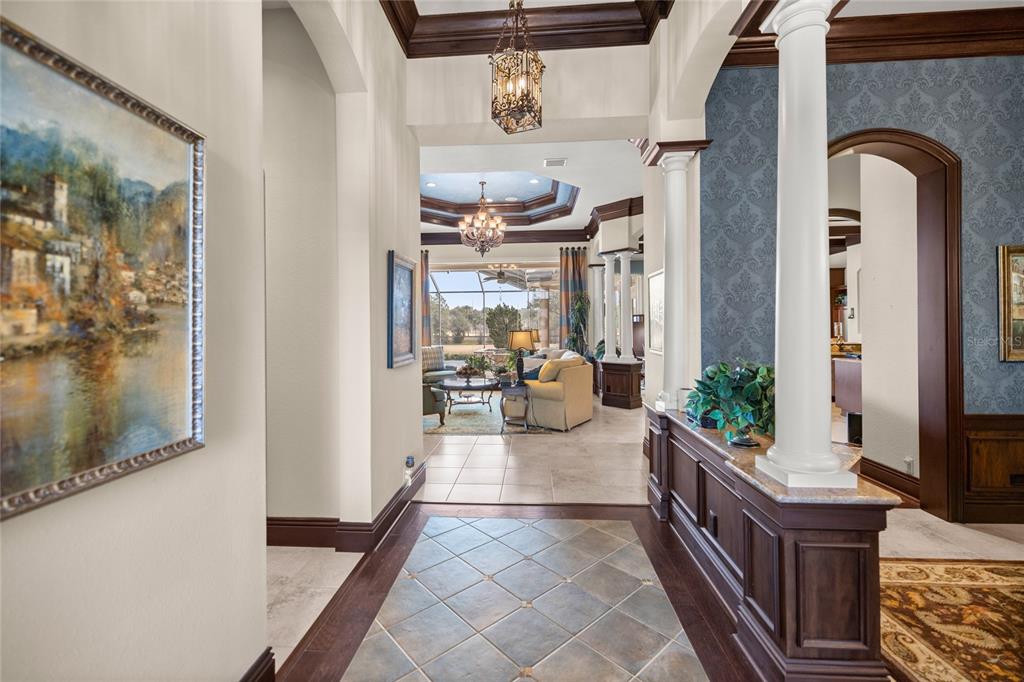 A foyer with tile flooring and wood trim leads into a living area with columns — 6861 SW 179TH AVENUE ROAD, DUNNELLON, FL