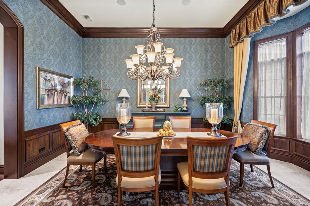 A formal dining room features blue damask wallpaper, dark wood wainscoting, and a large chandelier — 6861 SW 179TH AVENUE ROAD, DUNNELLON, FL
