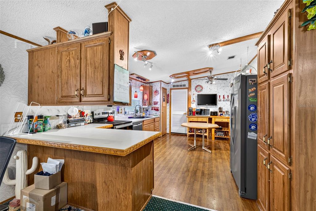 A kitchen features wood cabinetry, a breakfast bar, and a dining area with a table — 16435 SWEETWATER ROAD, DADE CITY, FL