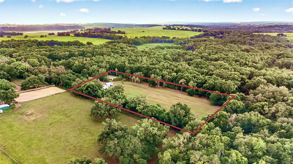 An aerial view shows a rectangular plot of land outlined in red amidst wooded surroundings — 16435 SWEETWATER ROAD, DADE CITY, FL