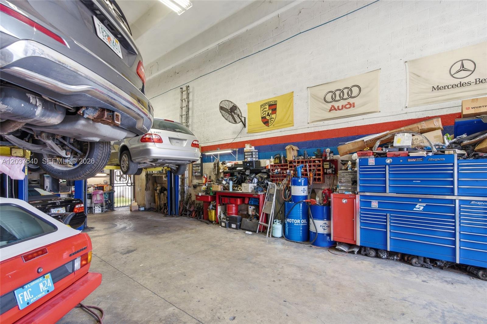 An auto repair shop features multiple cars on lifts, tool chests, and wall-mounted brand banners — 11950 SW 144th Ct # 3, Miami FL 33186, MIAMI, FL